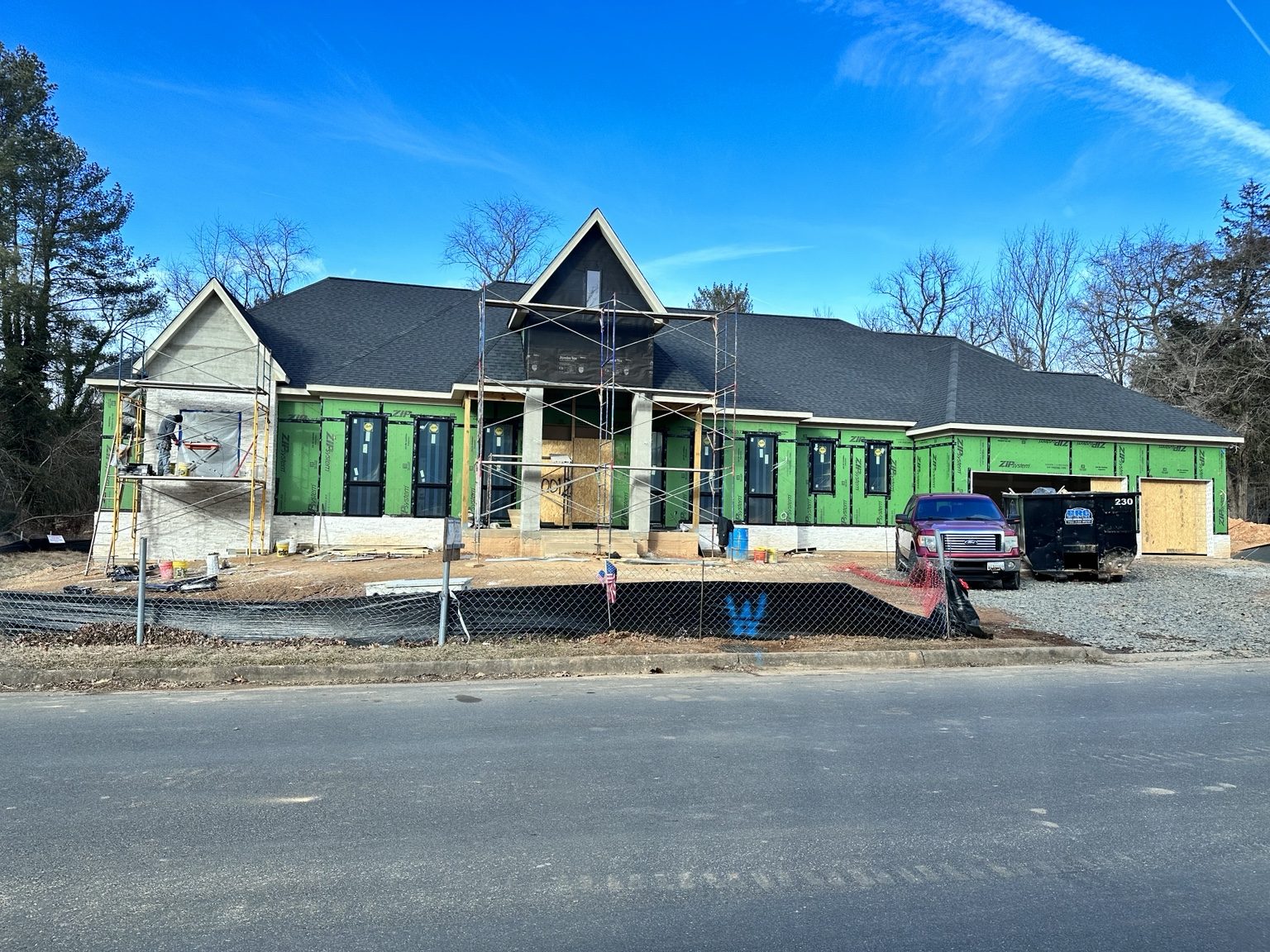 Custom home under construction with exterior sheathing and roof installed